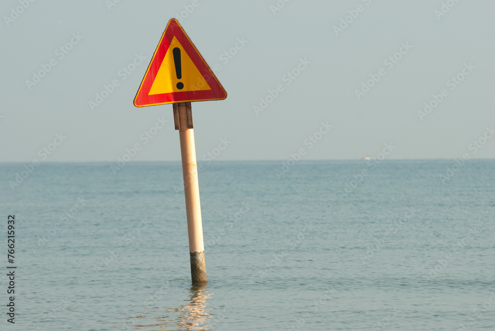General stock image - Sign with an exclamation mark sticking out of the Adriatic Sea at Rimini. .Metaphor - sea level rising.