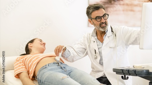 Happy doctor doing abdomen ultrasound examination of woman in clinic