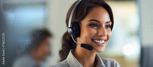 A cheerful female in a call center environment, smiling while using a headset and microphone to assist customers and make phone calls