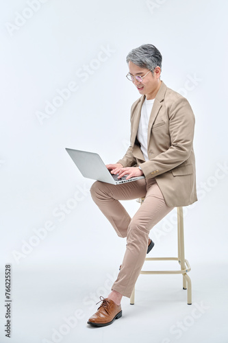 A middle-aged male teacher in a suit and glasses is sitting in a chair, holding a laptop, working with various expressions and poses.
