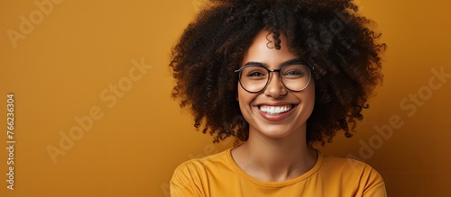 A happy woman with stylish eyeglasses is smiling brightly while dressed in a vibrant yellow shirt photo