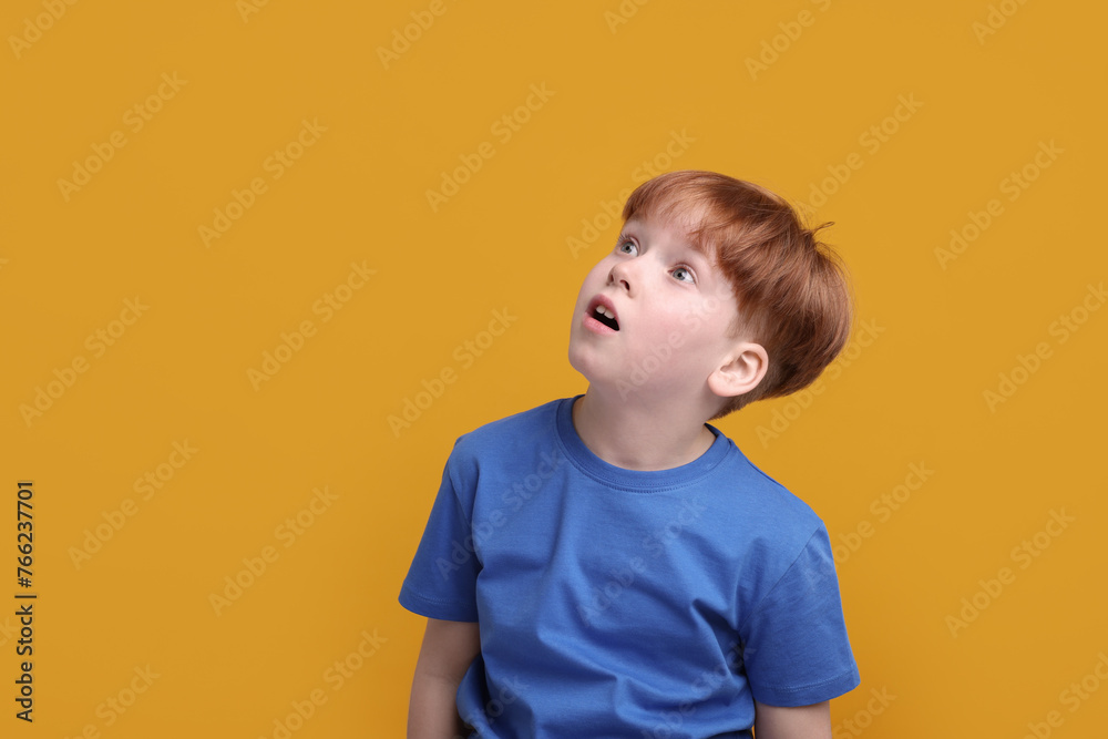 Portrait of surprised little boy on orange background, space for text Portrait of surprised little boy on orange background, space for text