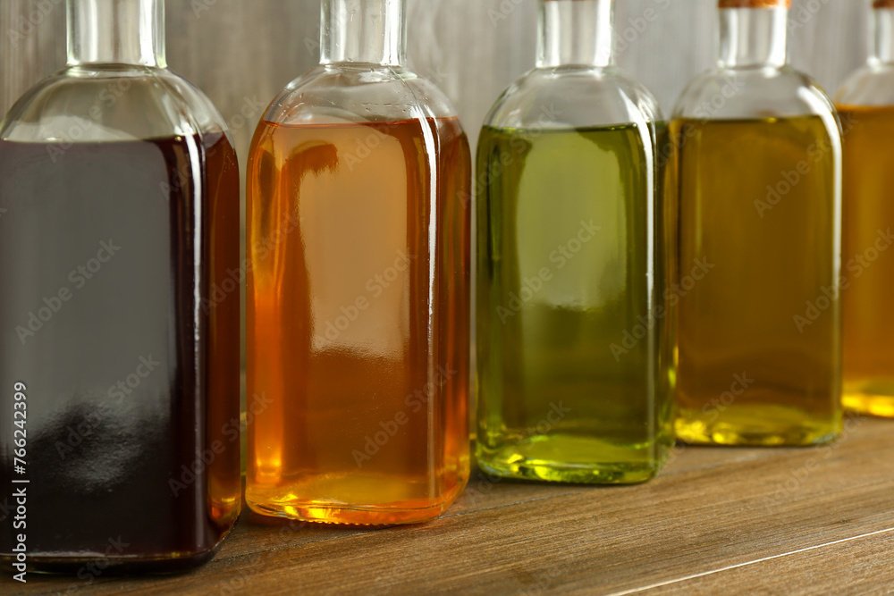 Vegetable fats. Different oils in glass bottles on wooden table, closeup Vegetable fats. Different oils in glass bottles on wooden table, closeup