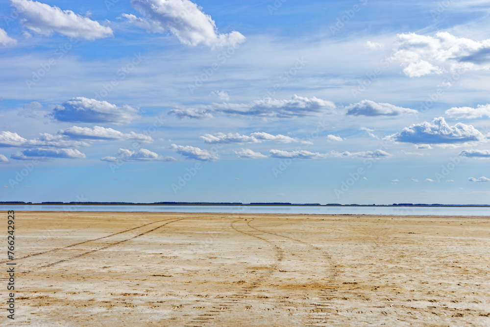 Beautiful shore of lake, white clouds on sky, water surface and sandy beach. Tranquil nature scene, summer sunlight day. Vibrant colored landscape in minimal style, panoramic cloudscape Beautiful shore of lake, white clouds on sky, water surface and sandy beach. Tranquil nature scene, summer sunlight day. Vibrant colored landscape in minimal style, panoramic cloudscape