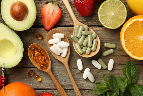 Different vitamin pills and fresh fruits on old wooden table, flat lay