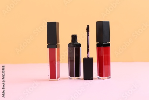 Different lip glosses and applicator on color background © New Africa
