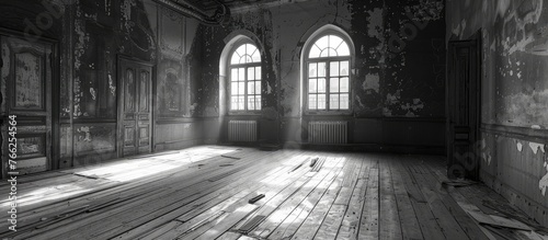 A blackandwhite photo of an empty room with wooden floors, arched windows, and a symmetrical layout. The darkness outside the windows contrasts with the light wood flooring