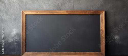 A brown rectangular blackboard with a wooden frame is placed in front of a flat panel display. The wood stain gives it a hardwood look, making it a multimedia display device photo