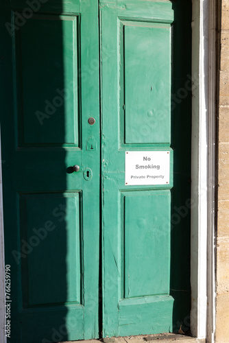 A "No Smoking, Private Property" sign on an old green door