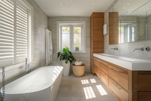 A spacious bathroom with grey tiles  wooden accents and large windows for natural light