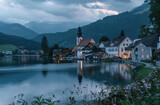 A picturesque view of Hall slammed, Austria with its iconic church and lake surrounded by mountains at dusk