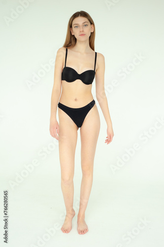 Snap Models. Full length portrait of a beautiful young woman in black bikini isolated on white background