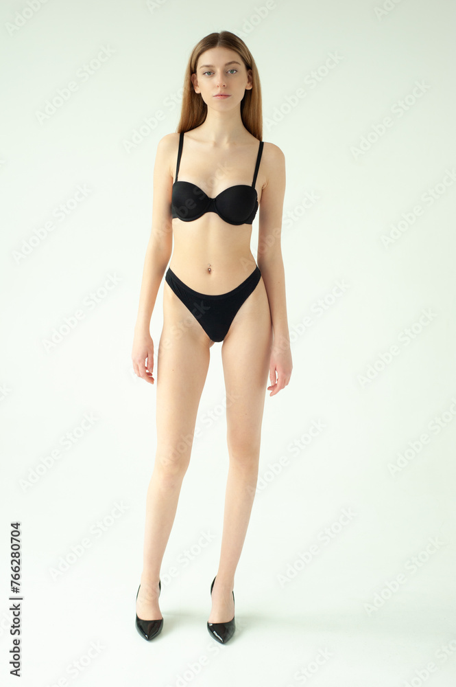 Snap Models. Full length portrait of a beautiful young woman in black bikini isolated on white background Snap Models. Full length portrait of a beautiful young woman in black bikini isolated on white background