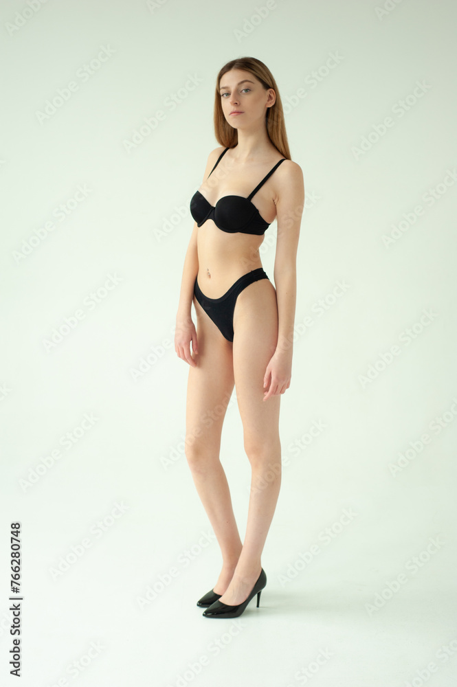 Snap Models. Full length portrait of a beautiful young woman in black bikini isolated on white background