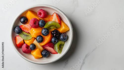 Top-down view white bowl filled with a vibrant assortment of freshly sliced fruits, mood conveyed is fresh, healthy, and inviting, copy space for text or other elements