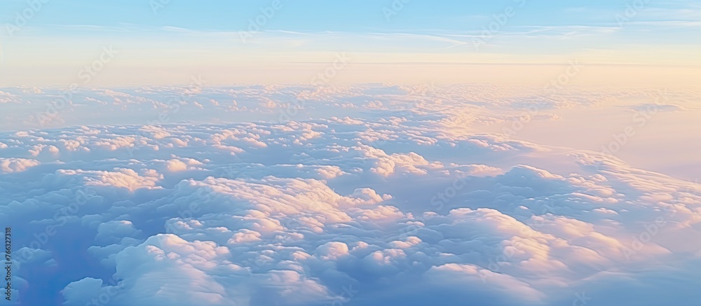 The image shows the aerial perspective from an airplane window, capturing a vast expanse of sky filled with fluffy clouds