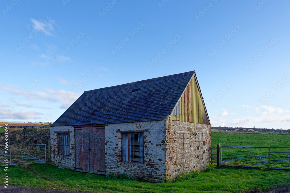 A derelict Farm building used previously for storage but now falling into disrepair on the side of a minor road in the farmland around Montrose.