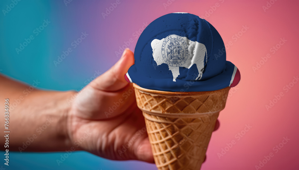 On a colorful background, a hand with ice cream in the form of the flag of Wyoming