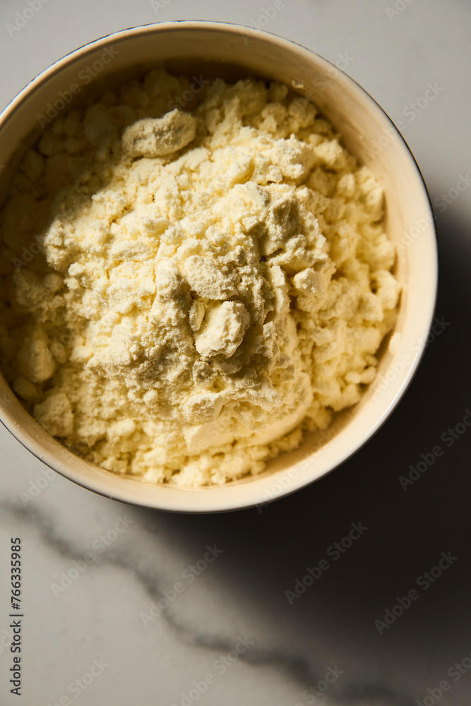 Dry powdered milk. Dehydrated Milk powder in the bowl on white marble background, Minimalistic food photo. Dry powdered milk. Dehydrated Milk powder in the bowl on white marble background, Minimalistic food photo.