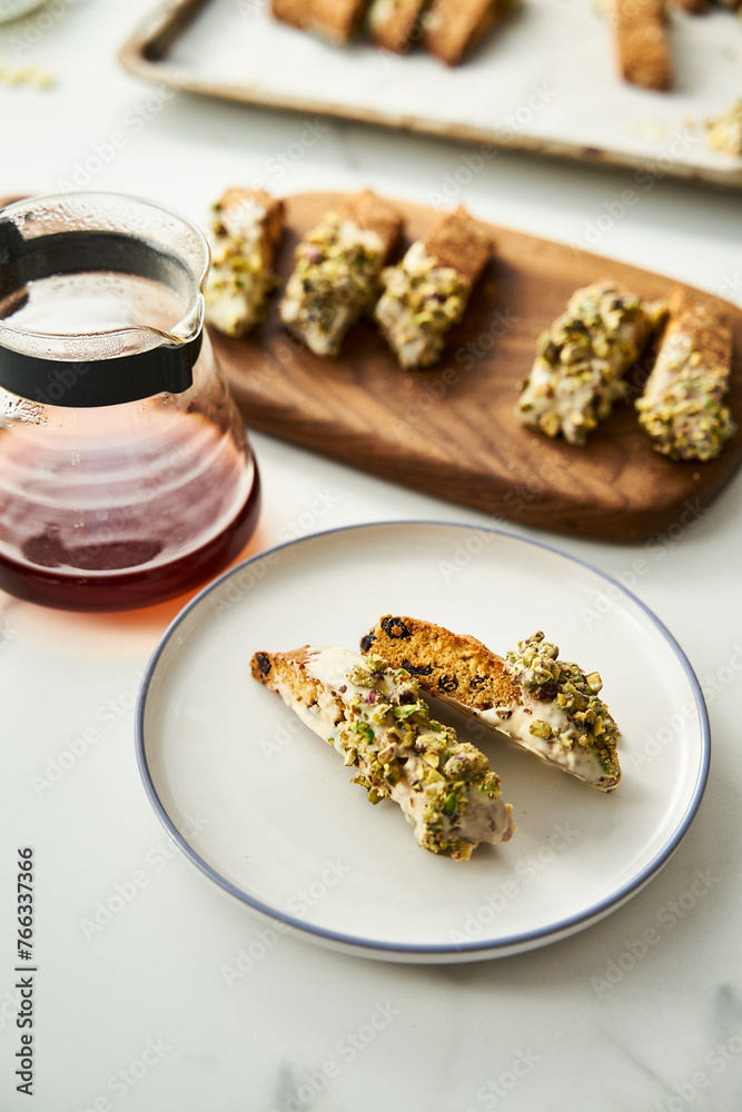 Golden Biscotti or Cantuccini on white plate on the white marble background.Traditional Sweet Italian cookies, two times baking, with nuts and dried cranberries served with filter coffee