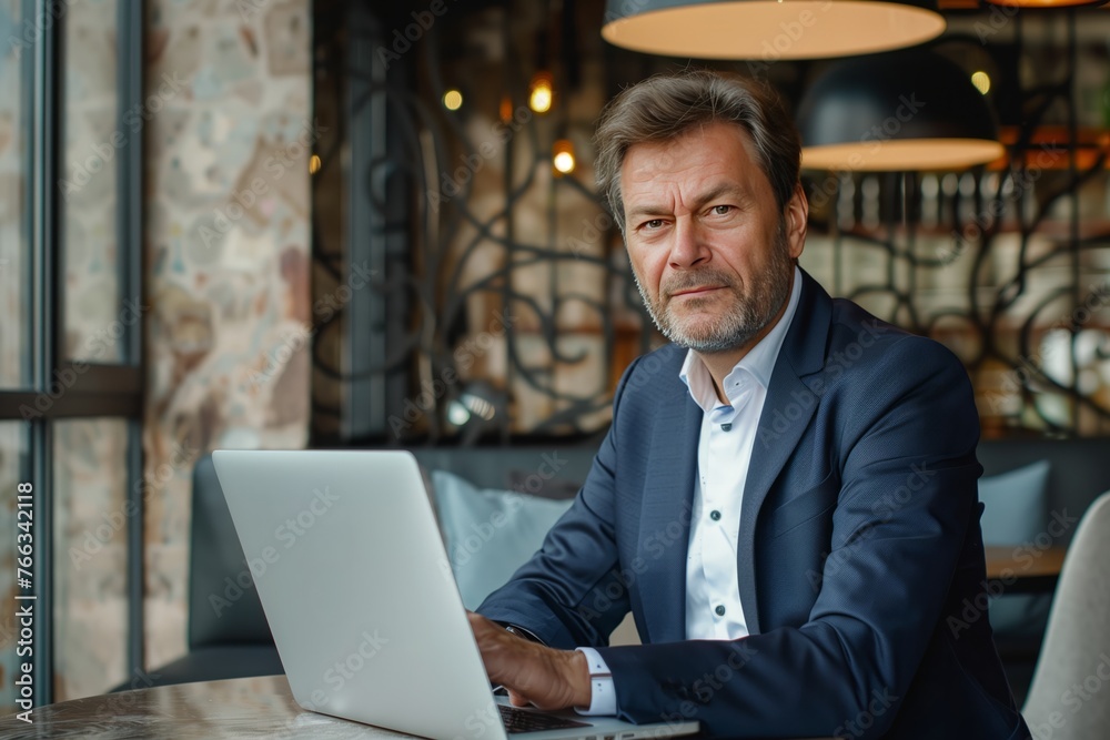 Businessman, digital nomad or freelancer working on a laptop in a cozy cafe. Productivity and tranquility, as the person blends remote job and relaxation in a comfortable environment.