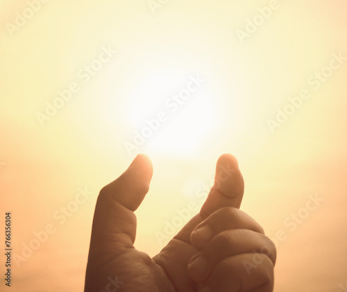 The light of the sun at fingertips. Present creative idea. Hand and warm sky background. Making big things smaller.
