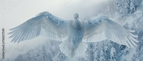  A large white bird, with wings spread out, is perched against snow-covered trees and a snowy mountain in the background