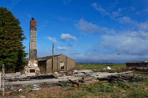 A chimney of a demolished house at Stracathro Wartime Airfield stands amongst the ruins of the various Airfield buildings now set in Farmland.