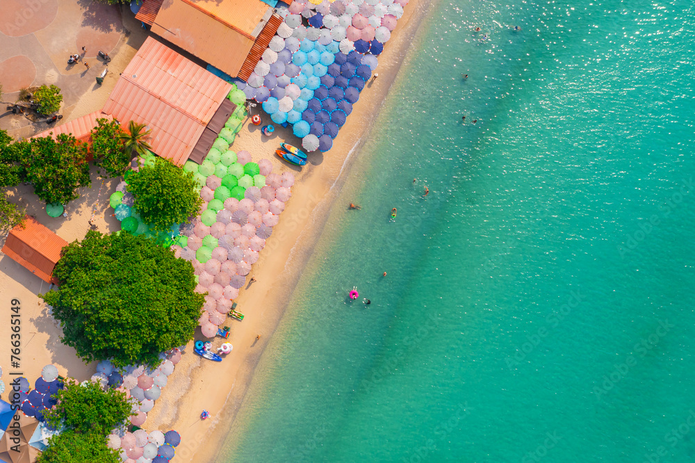 Aerial view view of the beach with umbrellas and bathing people, inflatable rings and boats, clear azure water