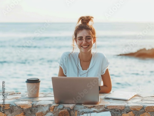 Happy female freelancer working on laptop at seashore with empty space for text