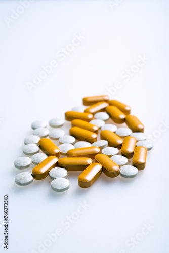 Witte en oranje pillen of supplementen ter verbetering van de gezondheid, tegen een witte achtergrond. photo