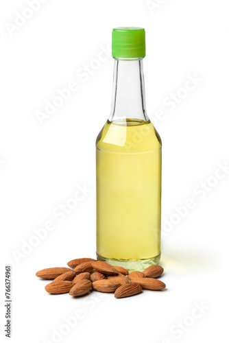 Single bottle with almond oil and a heap of almonds isolated on white background close up © Picture Partners