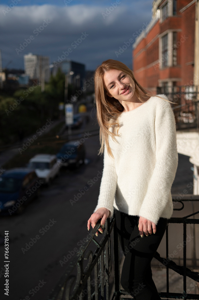 Young attractive blonde woman standing on the balcony