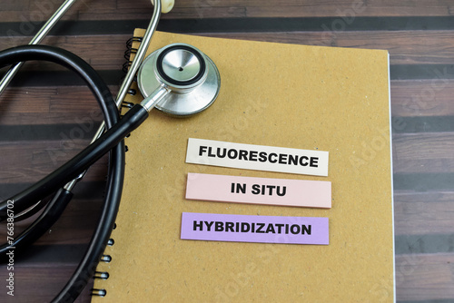 Concept of Fluorescence in Situ Hybridization write on sticky notes with stethoscope isolated on Wooden Table. photo