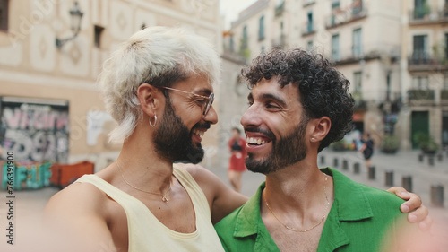 Homosexual couple stands hugging and takes selfie on street of old city