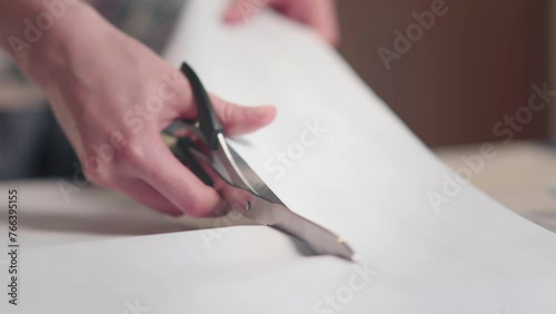 Workplace of seamstress. Close up dressmaker cuts dress detail with scissors