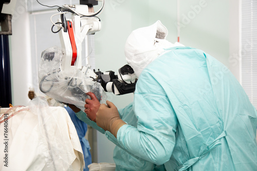 A neurosurgeon doctor looks into a microscope during an operation. Neurosurgery and microsurgery. Real operating room. 