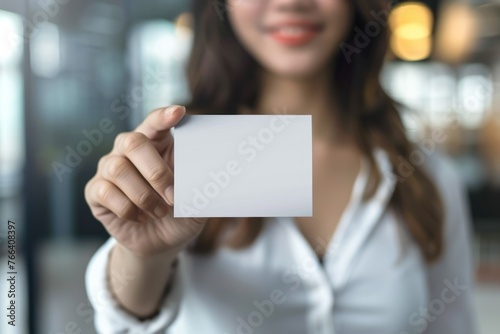 A young woman holding a blank business card Isolated on white background