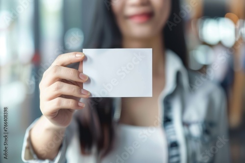 A young woman holding a blank business card office bokeh