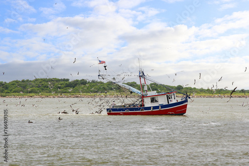 A fishing boat surrounded by sea birds trawls for fish as it heads out of Galveston Bay, Texas, on its way to Gulf Coast Waters