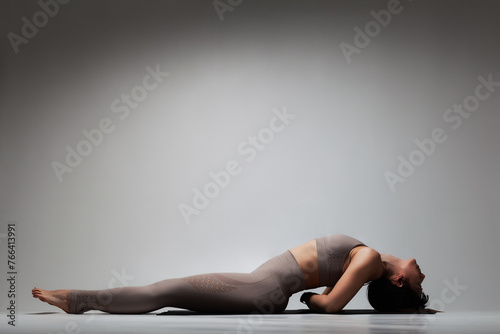 Beautiful caucasian woman in yoga pose. Half silhouette shot of a girl making stretching exercises.