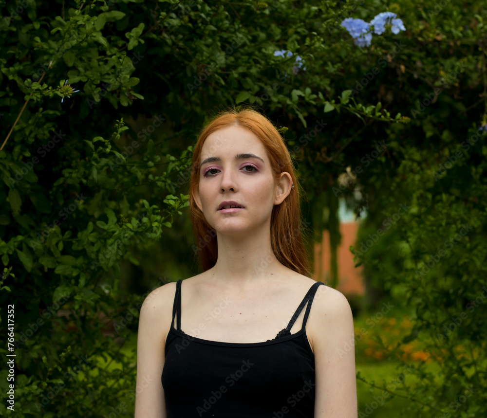 Close up photo of a beautiful caucasian ginger woman outdoors with a green natural background Close up photo of a beautiful caucasian ginger woman outdoors with a green natural background