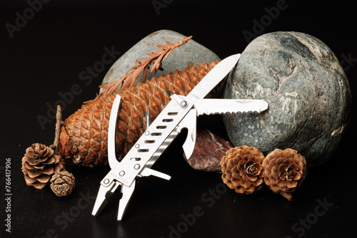 A multi-functional pocket knife with rocks ash the black background photo