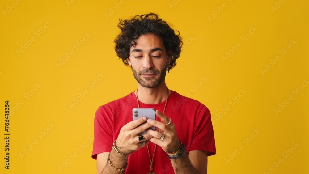 Man using mobile phone, typing massages isolated on yellow background in studio Man using mobile phone, typing massages isolated on yellow background in studio