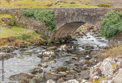 A shallow stream flowing quickly under an old stone bridge
