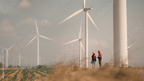Young man and woman maintenance engineer team. two engineer operate wind turbine. Engineer and worker discussing on a wind turbine farm. Wind Turbine. Maintenance Workers. renewable energies..