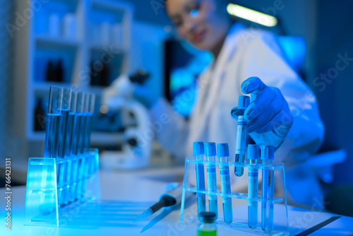 A woman in a lab coat is holding a syringe