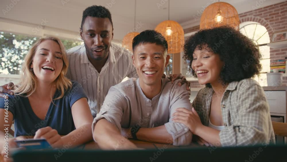 Multi-cultural group of friends at home using credit card to book vacation tickets or shop online with laptop computer - shot in real time Multi-cultural group of friends at home using credit card to book vacation tickets or shop online with laptop computer - shot in real time