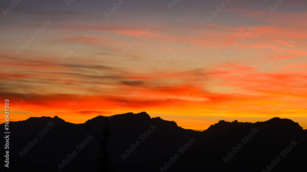 Burning clouds during sunset with mountain landscape