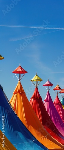 Vibrant carnival tents in a row, each with unique, flamboyant designs under a clear blue sky